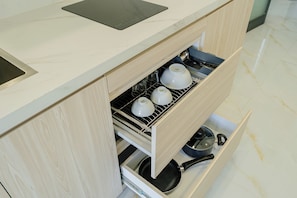 Uma cozinha com forno embutido, micro-ondas e gaveta com utensílios de cozinha.