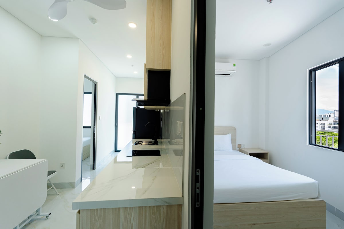 Una habitación de hotel moderna con una cama, un escritorio y una kitchenette.