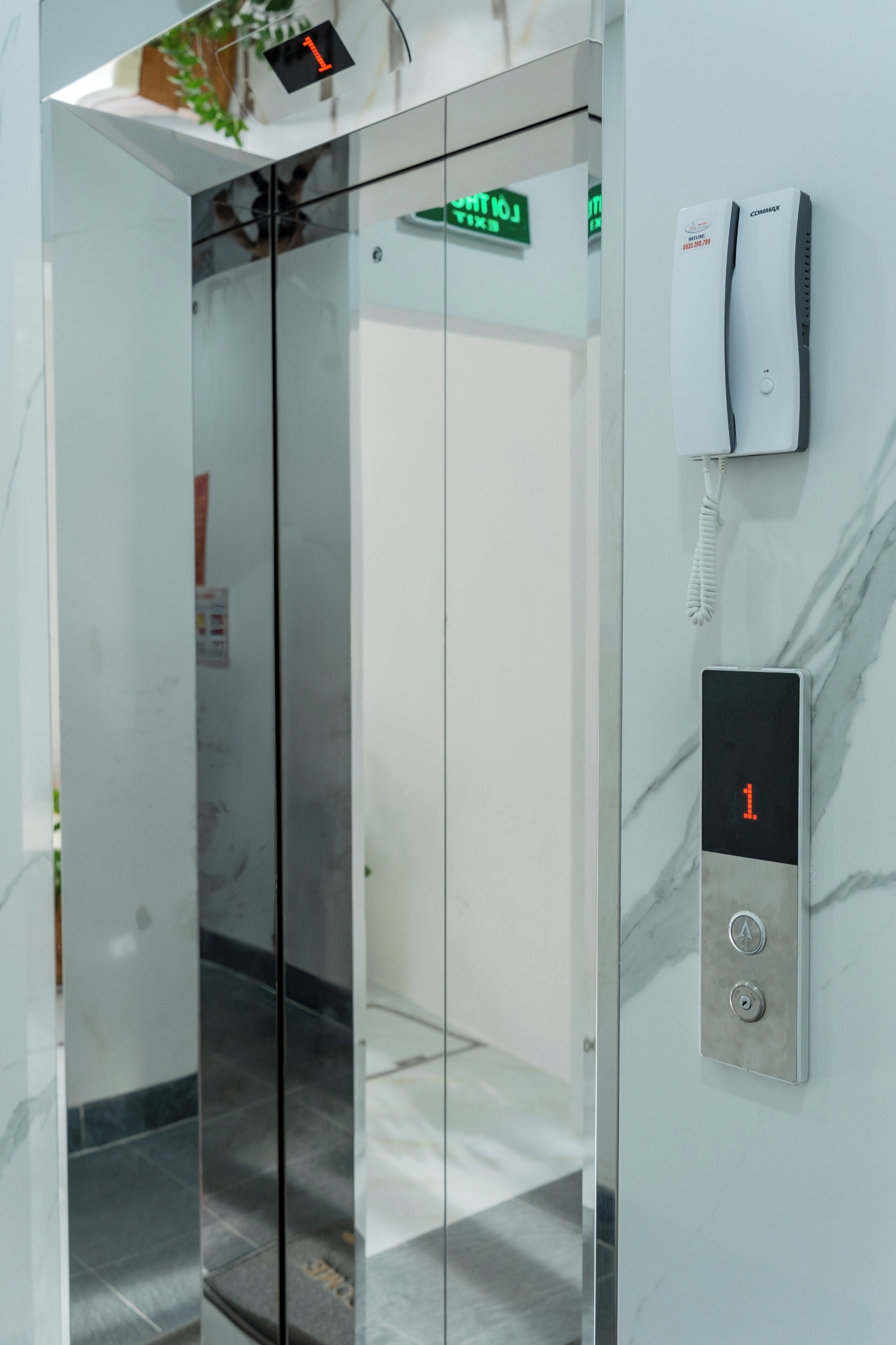 An elevator with a digital display, a phone, and a sign indicating the floor.
