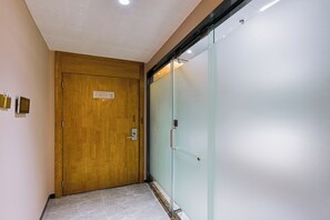 A hallway with a wooden door and a frosted glass partition.