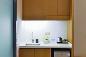 A modern kitchen with a stainless steel sink, a kettle, and a water dispenser.
