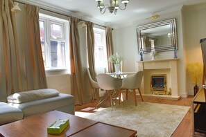 A living room with a sofa, a table with a tissue box, a fireplace, and a mirror on the wall. - Elegant Wimbledon Apartment (London)
