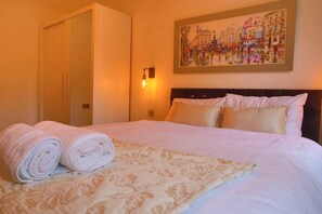 Una habitación de hotel con una cama, un cuadro en la pared y una toalla enrollada sobre la cama.