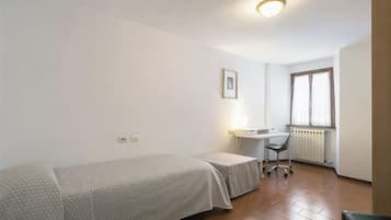 A small, clean room with a single bed, a desk, and a chair.