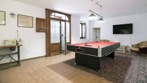 A room with a pool table, a sewing machine, a television, and a door leading to another room.