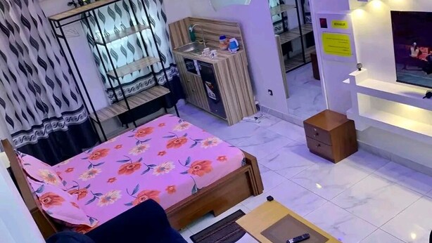 Una sala moderna con cama, sofá y una pequeña cocina.