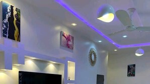Una sala de estar moderna con televisor de pantalla plana, estanterías empotradas, ventilador de techo y una cama.