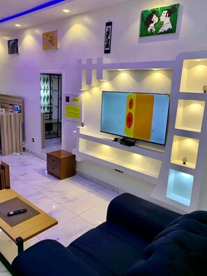 Una sala de estar moderna con un televisor de pantalla plana, estantes empotrados, un sofá y una mesa de centro.