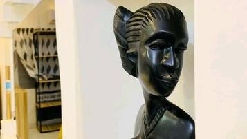 Eine Skulptur einer menschlichen Figur steht auf einem weißen Regal in einem Zimmer mit weißen Wänden und einem gefliesten Boden.