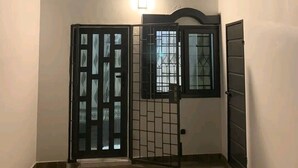 Una habitación de esquina con piso de madera, un portón negro y un ventanal con una lámpara arriba.