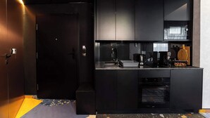Uma cozinha moderna com armários pretos, forno embutido, micro-ondas e máquina de café.