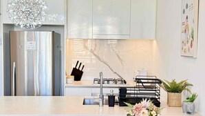 A modern kitchen with a marble backsplash, stainless steel appliances, and a black kitchen island with a vase of flowers. - Prime 2BR Location - Pool & Parking @BCT 1004 (South Brisbane)