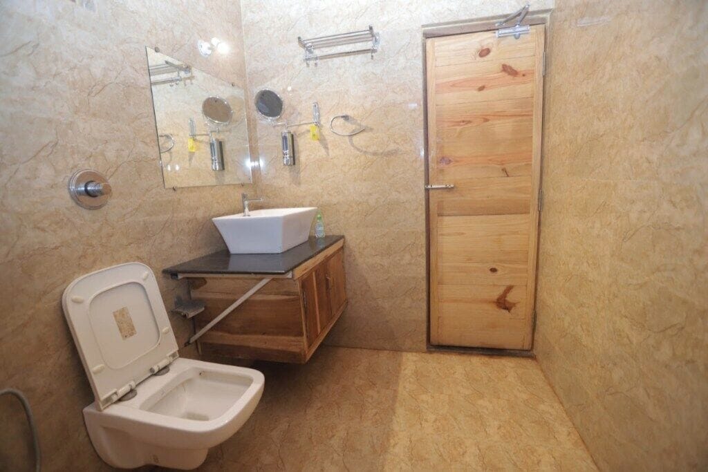Ein kleines Badezimmer mit Toilette, Waschbecken, Spiegel und Holztür.