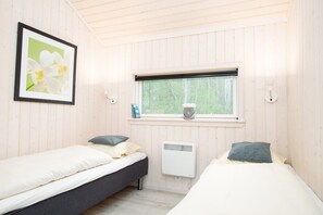 A room with two beds, a window with a view of trees, a radiator, and a framed picture on the wall. - Grobenbrode Baltic Horizon Haven (Grossenbrode)
