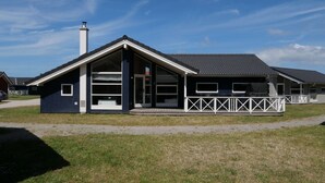 A modern building with a sloped roof, large windows, and a fenced outdoor area. - Grobenbrode Baltic Horizon Haven (Grossenbrode)