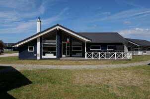 A modern building with a sloped roof, large windows, and a fenced outdoor area.
