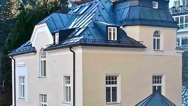 Un immeuble à plusieurs étages, doté d’une façade beige et d’un toit foncé.