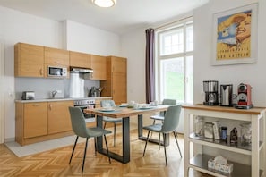 A compact kitchen with wooden cabinets, a microwave, a stove, and a dining area with a table and chairs.