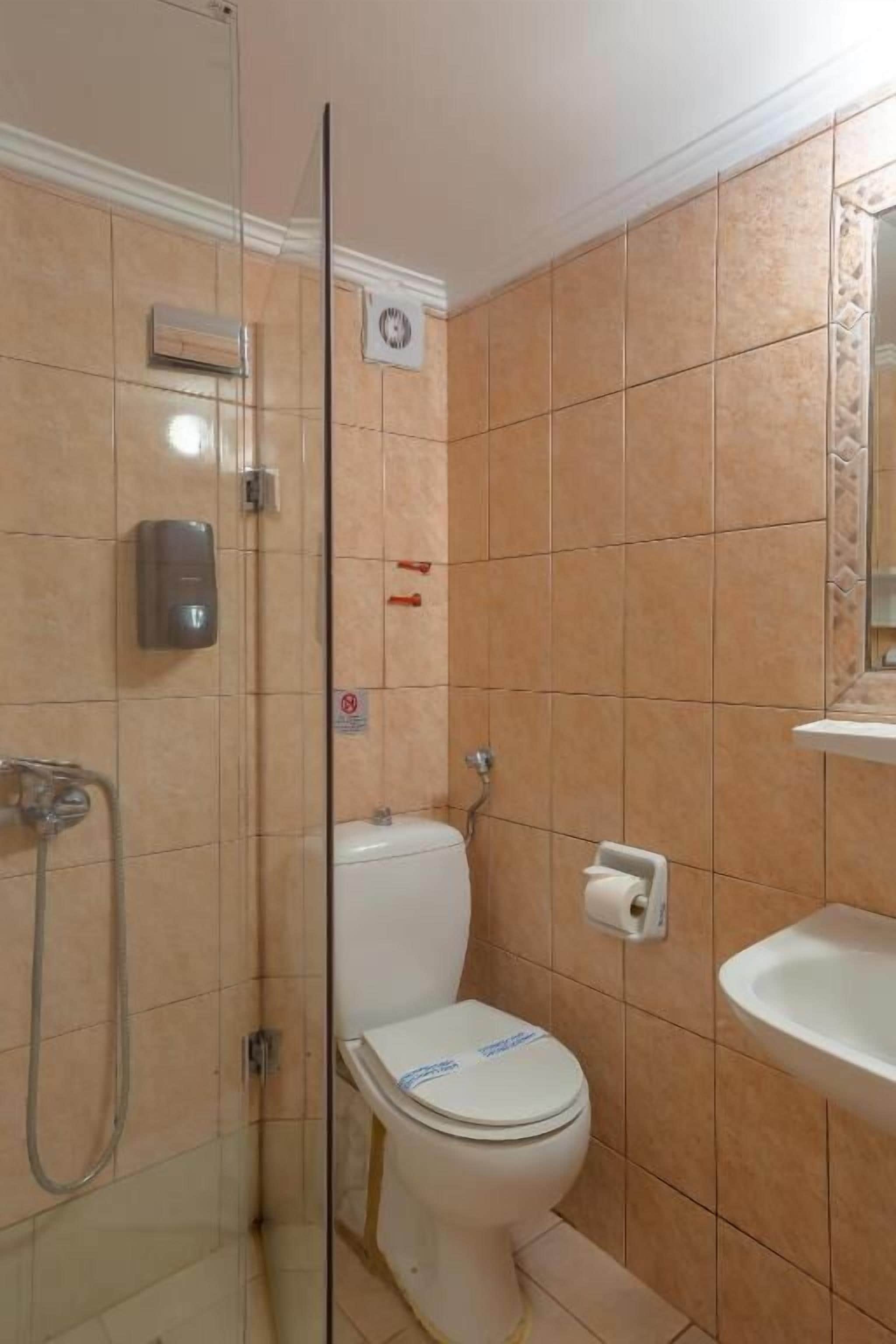 A bathroom with a glass shower enclosure, a toilet, and a sink.