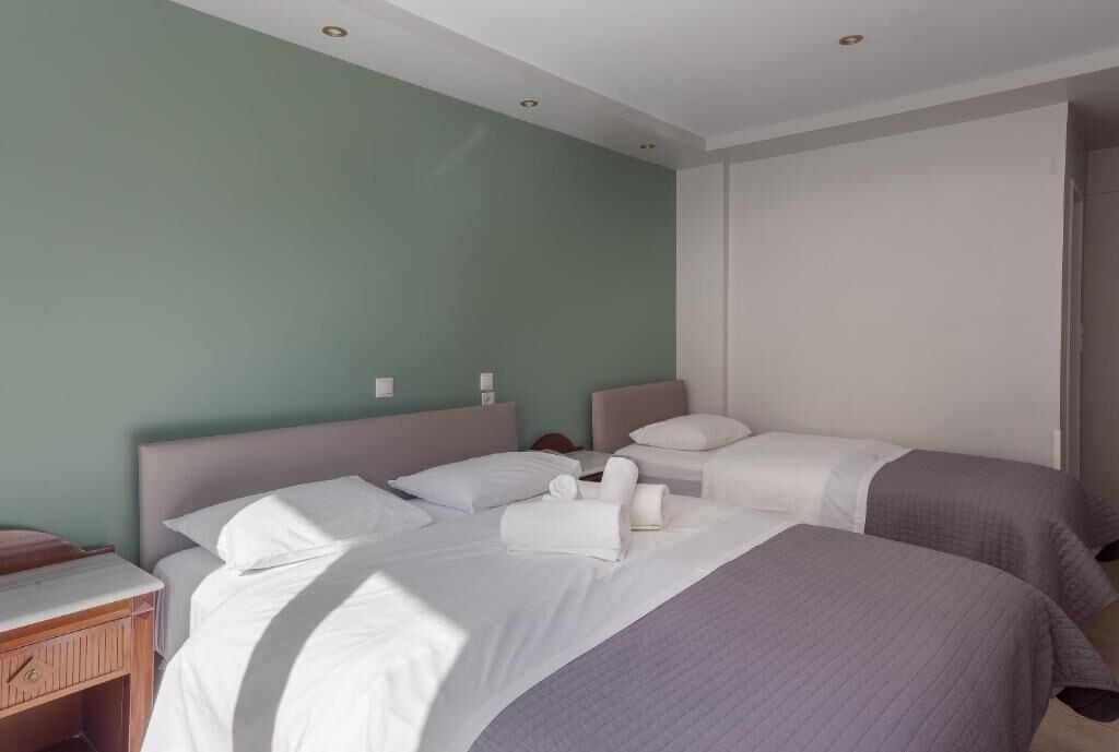 A hotel room with two beds, a nightstand, and a window.