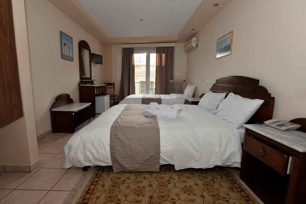 Una habitación de hotel con una cama grande, un escritorio, una silla, un aparador y una ventana con cortinas.
