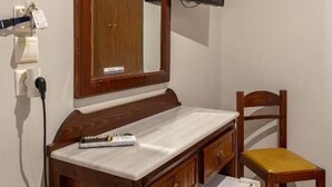 A bathroom with a wooden vanity, a mirror, a television mounted on the wall, and a chair.