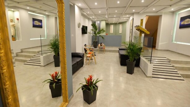 A modern interior with a reception desk, seating area, and a staircase leading to upper floors.