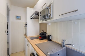 A compact kitchenette with a microwave, kettle, and coffee maker on the counter. - Orphée - Cozy Studio | Near the Train Station | Central (Cannes)