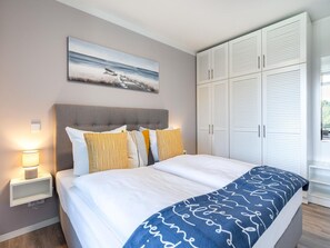 Ein Schlafzimmer mit Bett, Nachttisch, Lampe, Kunstwerk und einem Kleiderschrank.