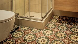 A bathroom with a glass-enclosed shower, a toilet, and a sink with a mirror above it.