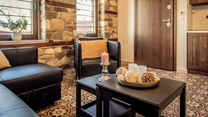 A cozy living room with a stone wall, a fireplace, a sofa, a coffee table with decorative items, and a view of the outside.
