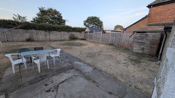 A backyard with a table and chairs, a brick wall, and a wooden fence. - Peaceful 4BDR Home with Garden in Slough (Berkshire)