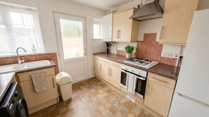 A kitchen with a sink, stove, oven, and cabinets. - Peaceful 4BDR Home with Garden in Slough (Berkshire)
