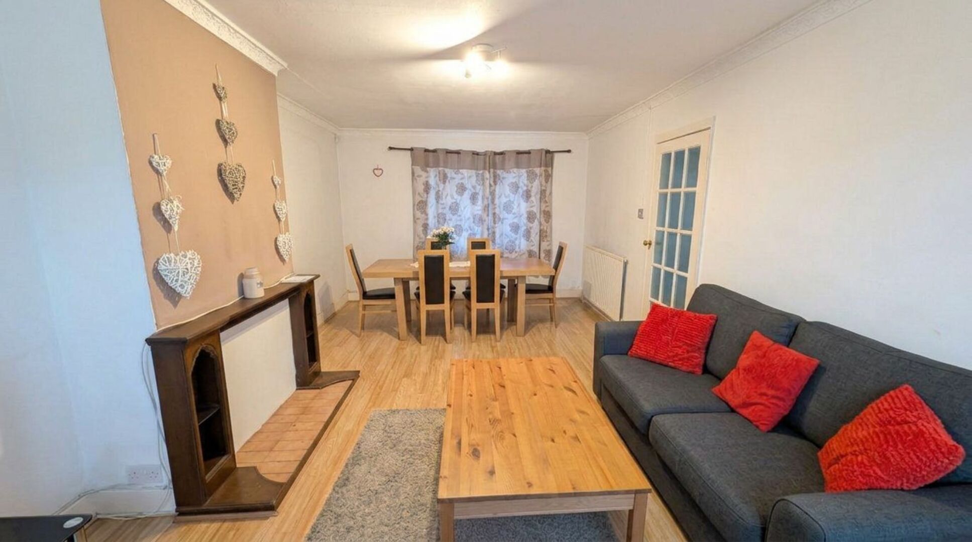 A living room with a sofa, a coffee table, a dining table with chairs, and a fireplace.