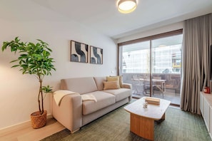 A modern living room with a sofa, a coffee table, a potted plant, and abstract art on the wall. - Premium Living with Pool & Garage by HostWise (Vila Nova de Gaia)