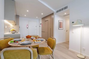 A modern dining area with a round table, yellow chairs, and a fruit bowl. - Premium Living with Pool & Garage by HostWise (Vila Nova de Gaia)
