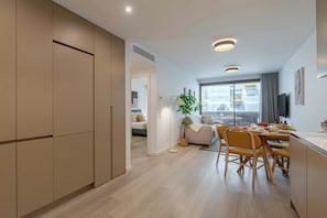 A modern kitchen with wooden cabinets, a dining area with a table and chairs, and a large window providing natural light. - Premium Living with Pool & Garage by HostWise (Vila Nova de Gaia)