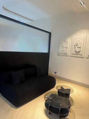 Ein modernes Wohnzimmer mit einer schwarzen Couch, einem Glastisch und an der Wand befestigter Kunst.