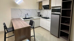 Una cocina moderna con una mesa de comedor de madera, sillas negras, una estufa empotrada y un refrigerador de acero inoxidable.