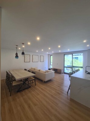 Ein großzügiger Wohnbereich mit Esstisch, Sofa und großen Fenstern mit Blick.