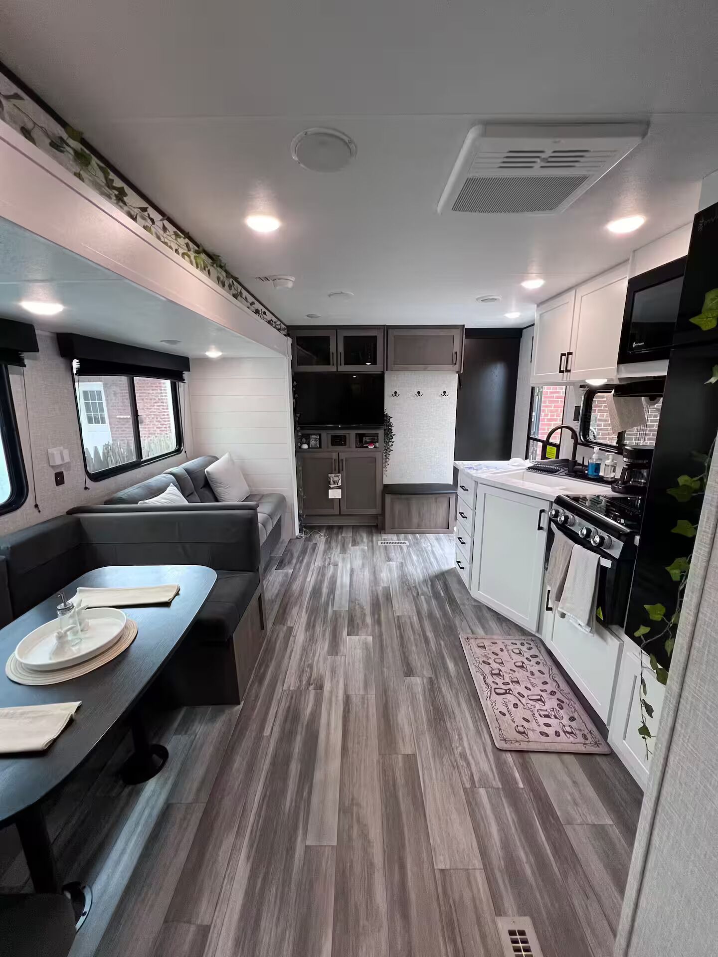 A compact RV interior with a dining area, kitchenette, and seating space.