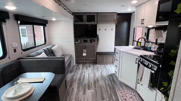 A compact RV interior with a dining area, kitchenette, and seating space.