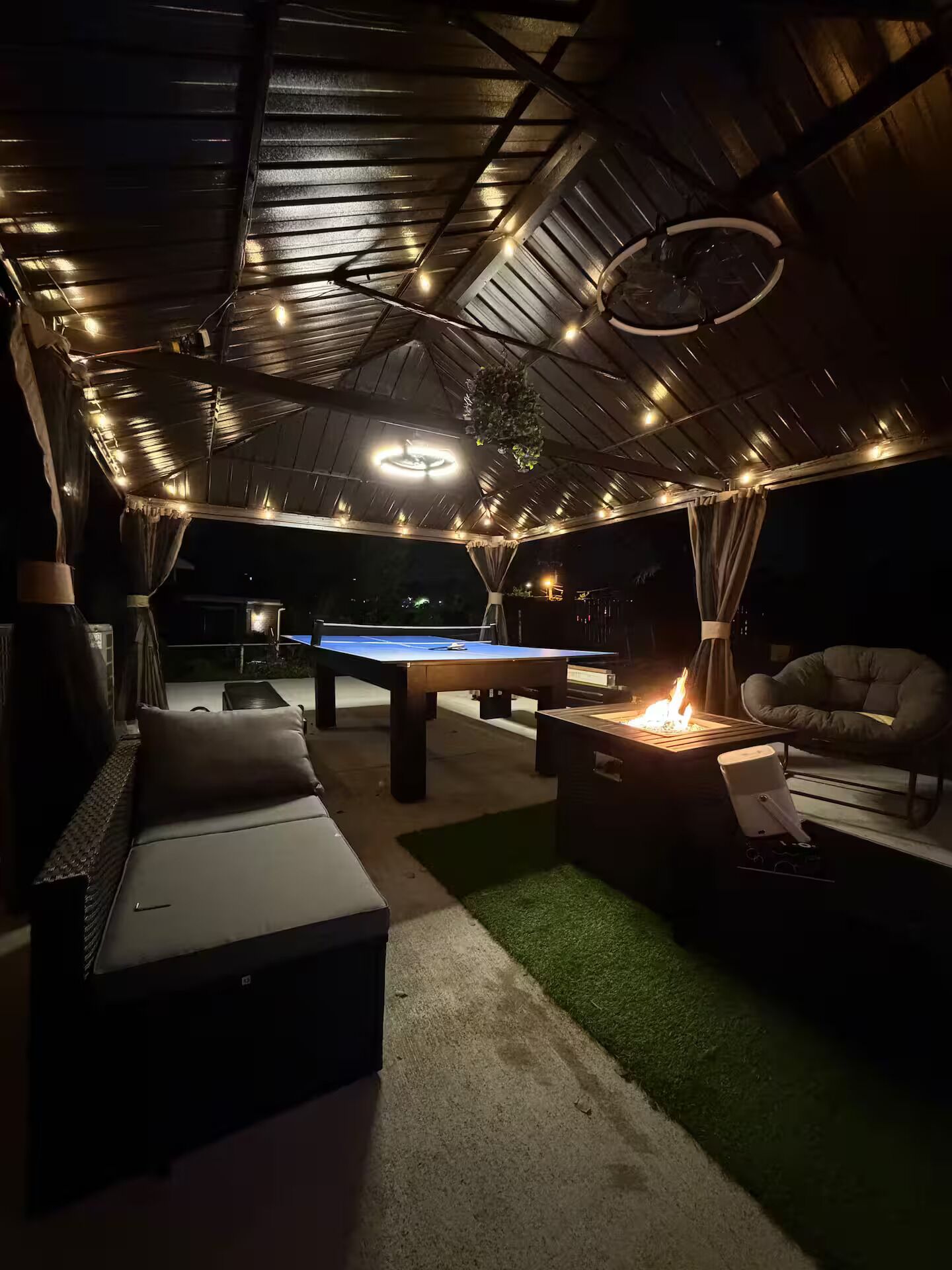 Un área de descanso al aire libre con mesa de billar, asientos y una chimenea.