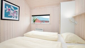 A bedroom with a bed, a window, a radiator, and a framed picture on the wall. - Charming Seaside Haven Oasis fur 6 (Grossenbrode)