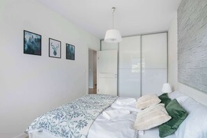 A bedroom with a bed, a wardrobe, and three framed pictures on the wall. - Blue and Beige Apartment | Mountain View | Parking (Szklarska Poręba)