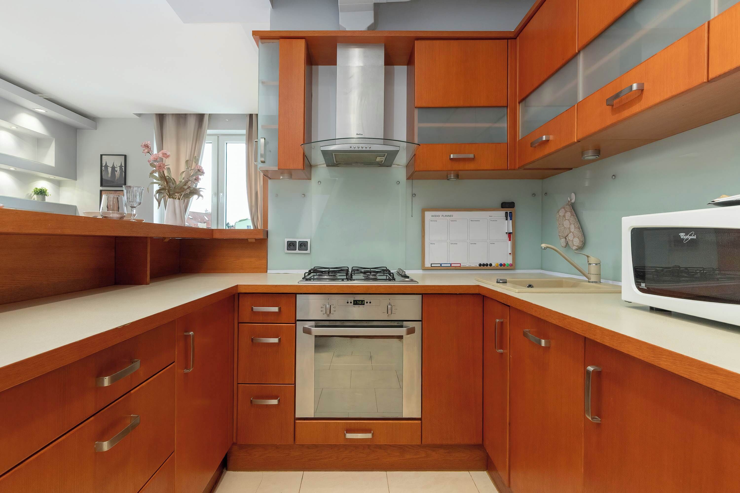 Una cocina moderna con armarios de madera, horno empotrado, cocina a gas y microondas.