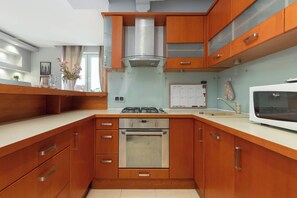 Une cuisine moderne avec des meubles en bois, un four encastré, une cuisinière à gaz et un four à micro-ondes.