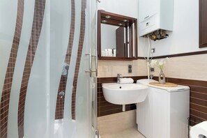 Une salle de bain moderne avec une douche à parois de verre, un lavabo blanc et un meuble-lavabo avec un miroir.