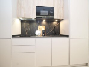 A modern kitchen with a built-in microwave, a black marble backsplash, and a stainless steel faucet. - Design studios in Pedregalejo - 4 guests (Málaga)