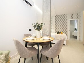 Een moderne eetruimte met een ronde tafel, vier stoelen en een vaas met planten.